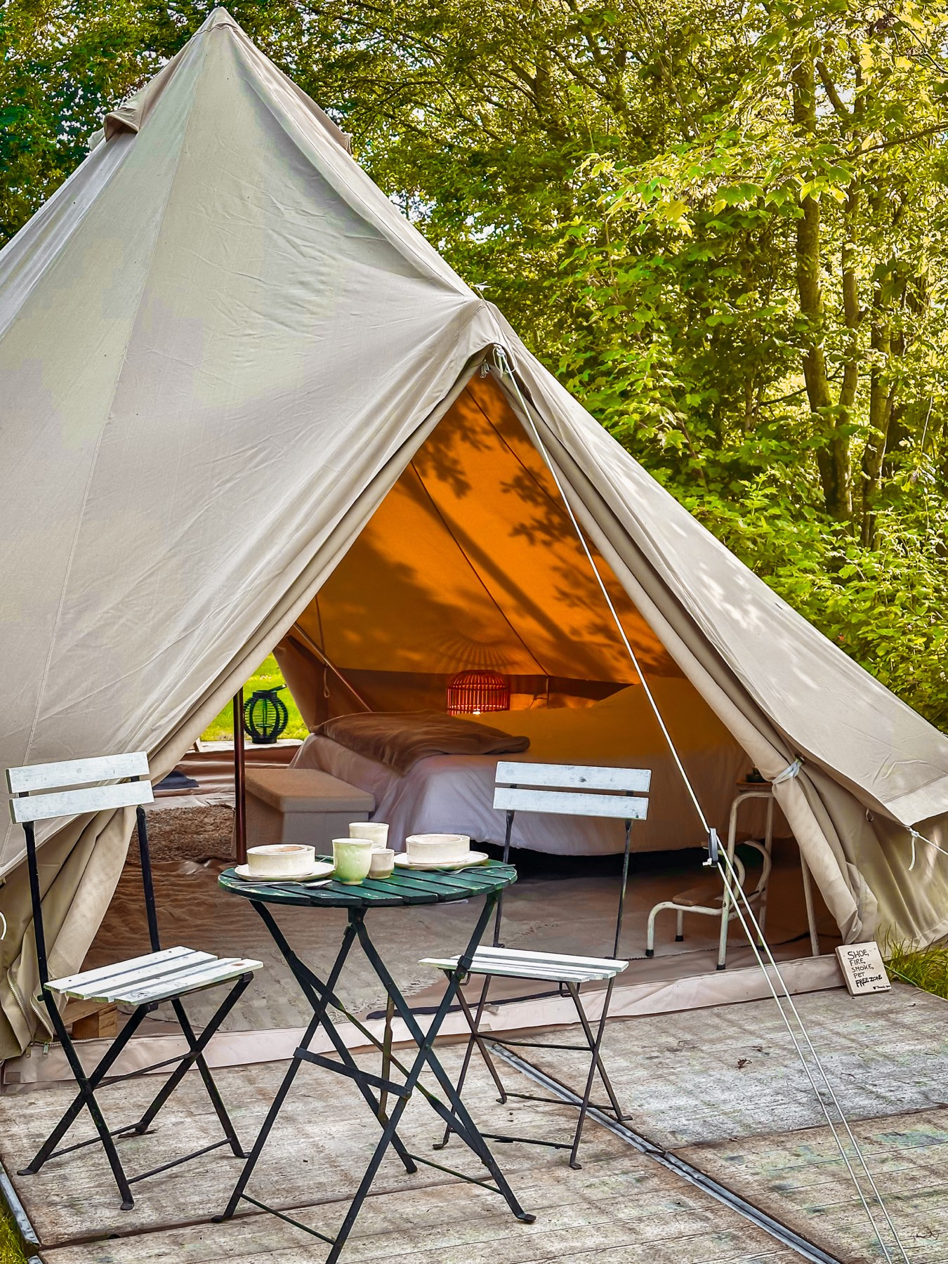 Bell tent met echt bed, lantaarns en een tafel buiten