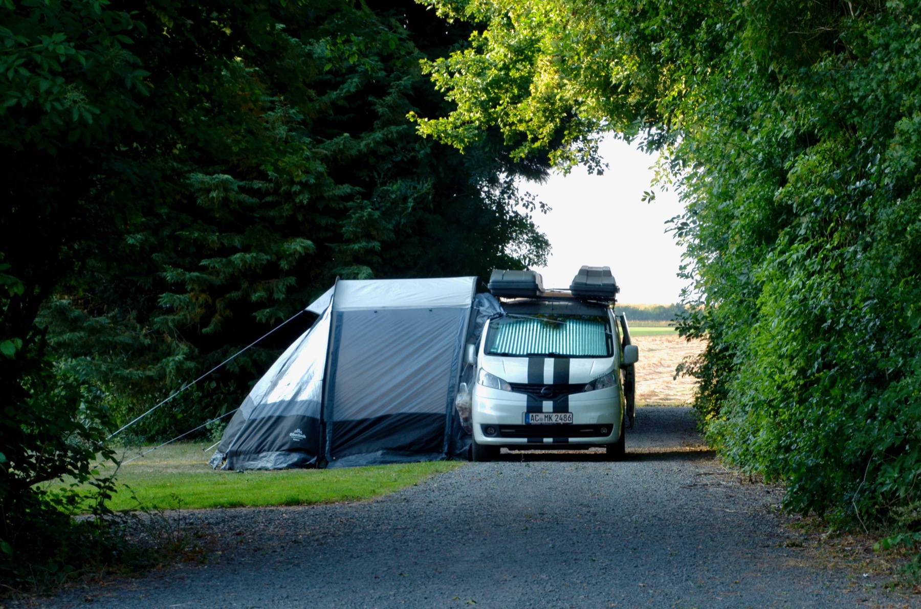 Tent en camper tussen de hagen op het kampeerveld